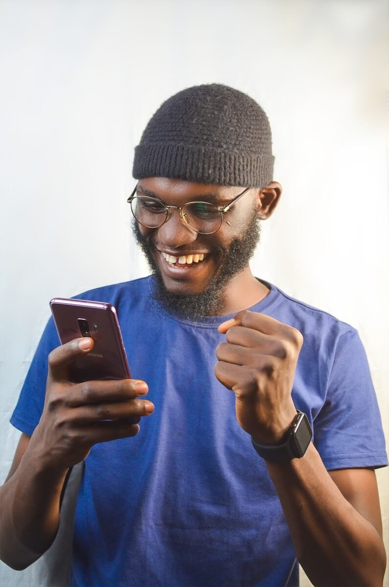 a man in a beanie is looking at his cell phone