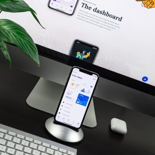 space gray iPhone X on stand near silver iMac and Apple Magic Keyboard